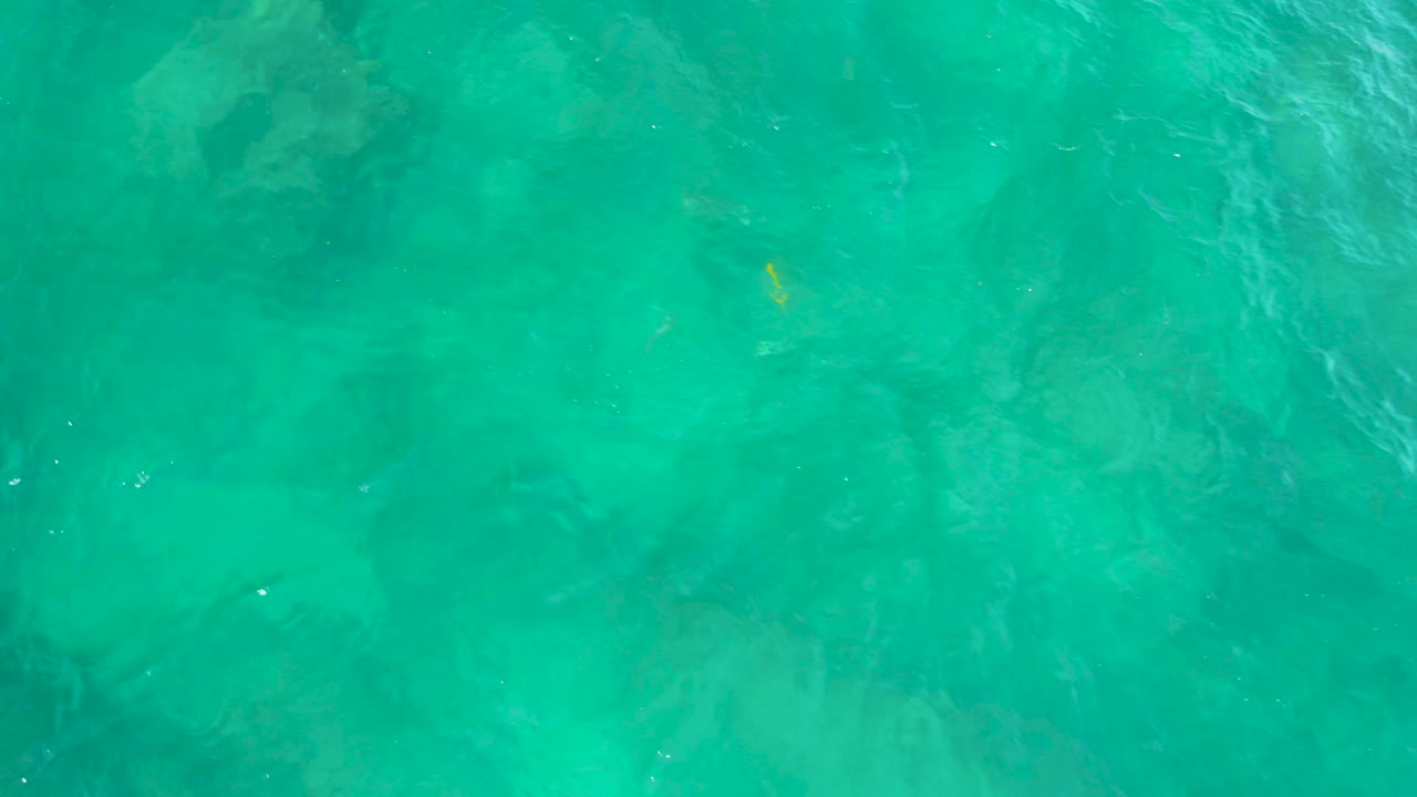 Overhead turquoise water at Shipwrecks Beach, Baja California Sur, with pale submerged rock or reef shapes softened by ripples, no visible people.