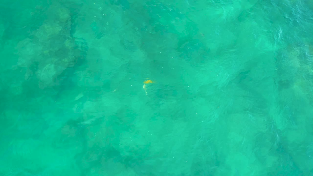 Green-blue water at Shipwrecks Beach in Baja California Sur, Mexico, with blurred darker rocks below the surface and no visible people.