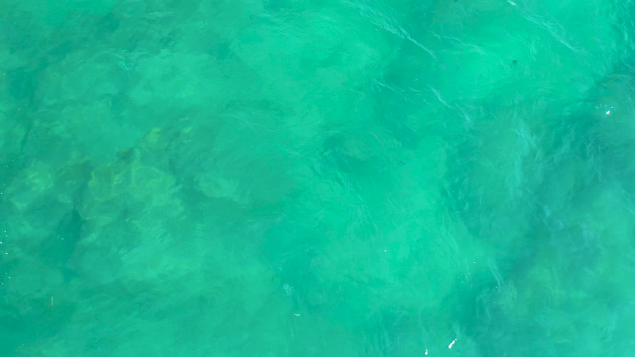 Turquoise ocean water seen from above with submerged dark shapes.