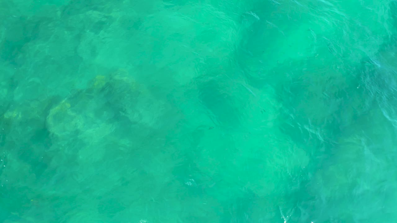 Translucent overhead ocean water at Shipwrecks Beach in Baja California Sur, Mexico, with mottled darker forms beneath the surface and no visible people.
