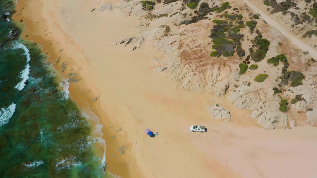 Aerial shoreline with waves on the left and rocky desert beach on the right