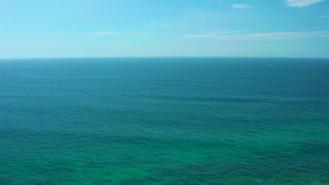 Open ocean with teal water and faint reef patches.