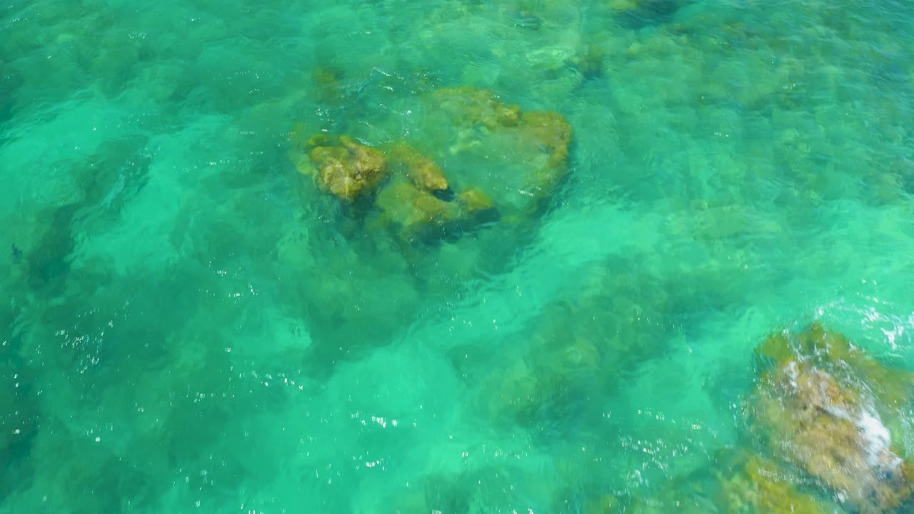 Submerged rocks beneath rippled green ocean