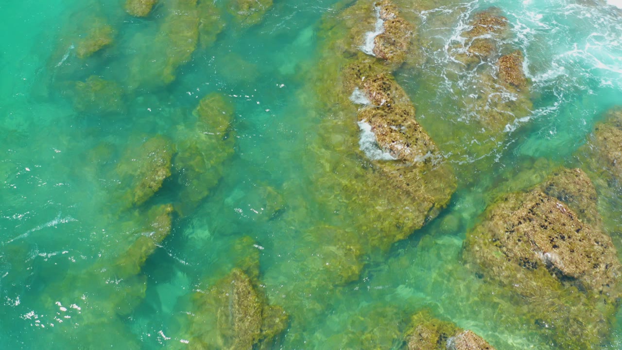 Overhead turquoise water and shallow rocks with small surf lines.