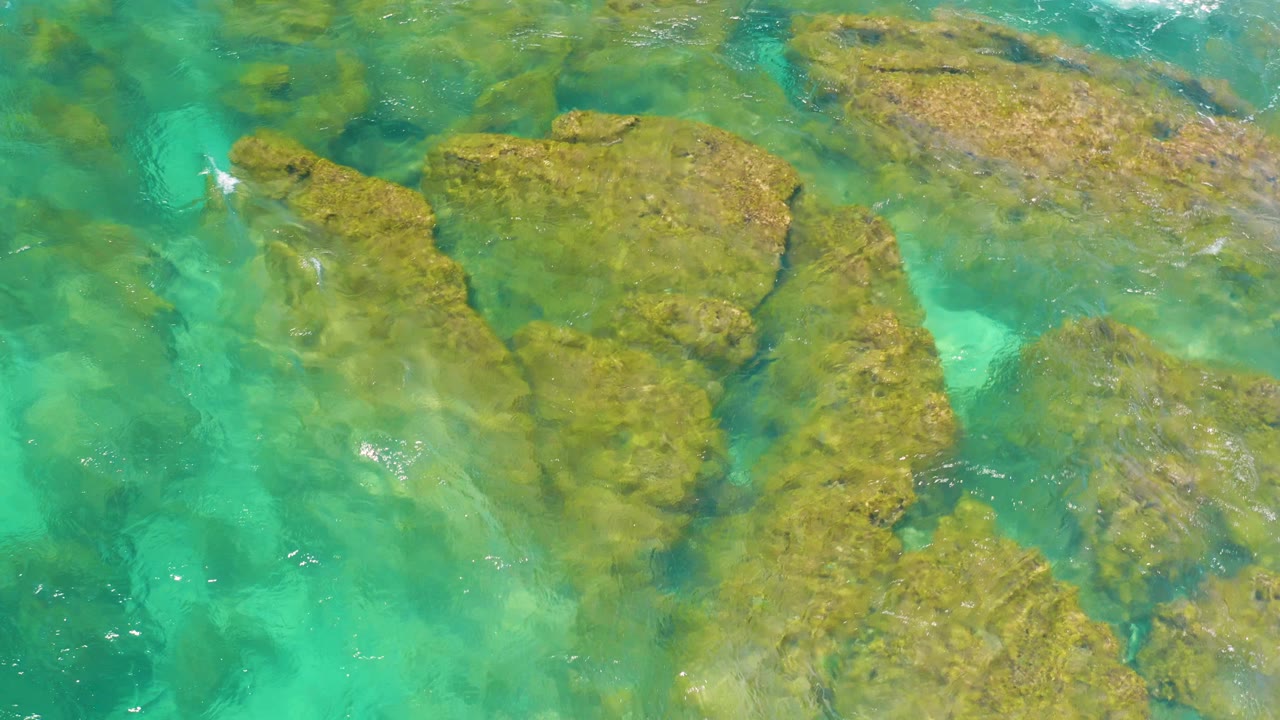 Overhead turquoise water covering brown rock shelves