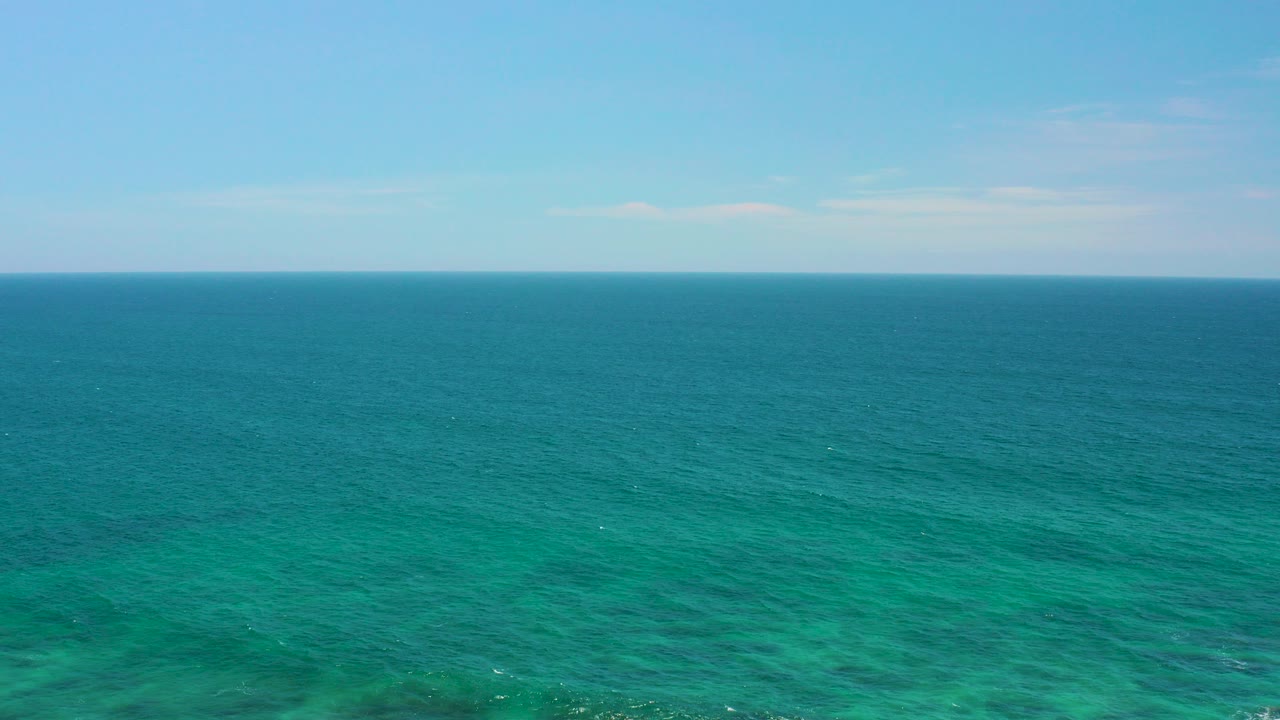 Opening frame of Shipwrecks Beach in Baja California Sur, Mexico, showing broad turquoise ocean below a pale blue sky with no visible people.