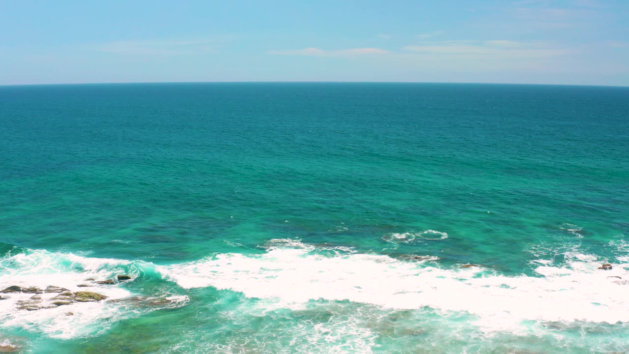The lower frame holds a rocky surf zone while wide turquoise water extends to the horizon at Shipwrecks Beach, Baja California Sur, and no people are visible.