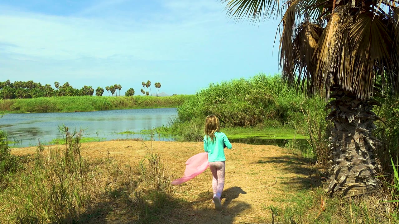 Girl walking away with pink cloth low at her side