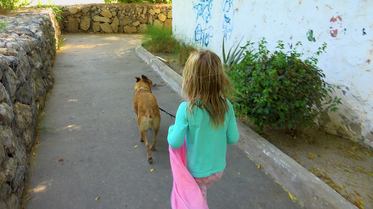 Girl follows a dog toward a bend in the path.