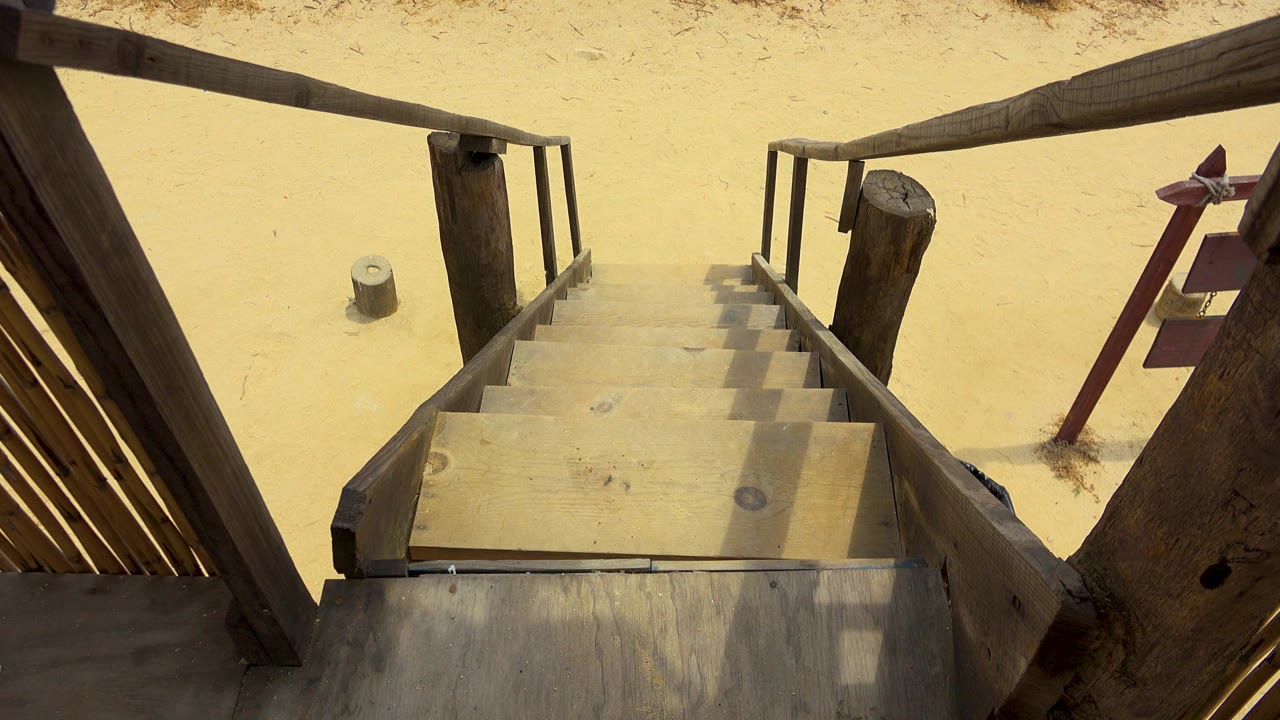 At three seconds, the San Jose Del Cabo stairway remains in a downward-looking composition, showing weathered boards, angular rail shadows, pale sand, and no visible people.