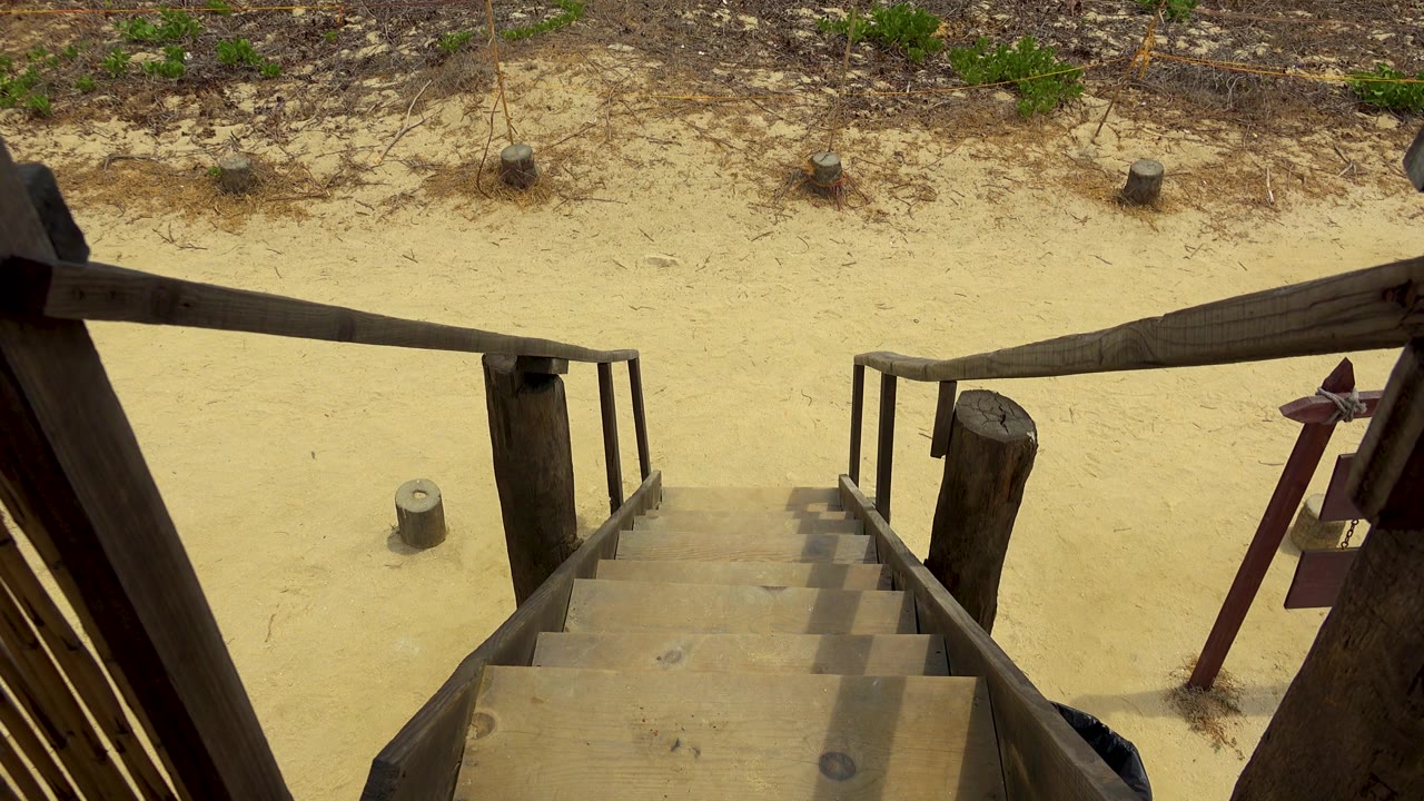 Wooden railings and steps remain prominent above sand and scrubby vegetation in San Jose Del Cabo, Mexico, with no visible people.