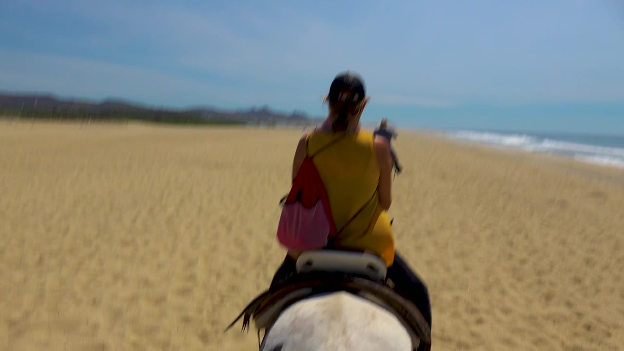 The rider appears smaller in the frame on the San Jose Del Cabo beach, leaving more open sand visible in front and a bright ocean strip along the right background.