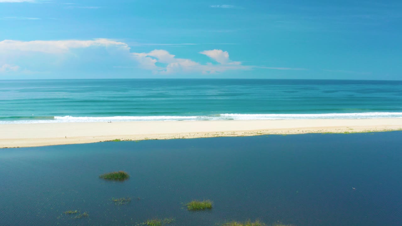 Aerial view of lagoon, sandy beach, surf, and blue sea