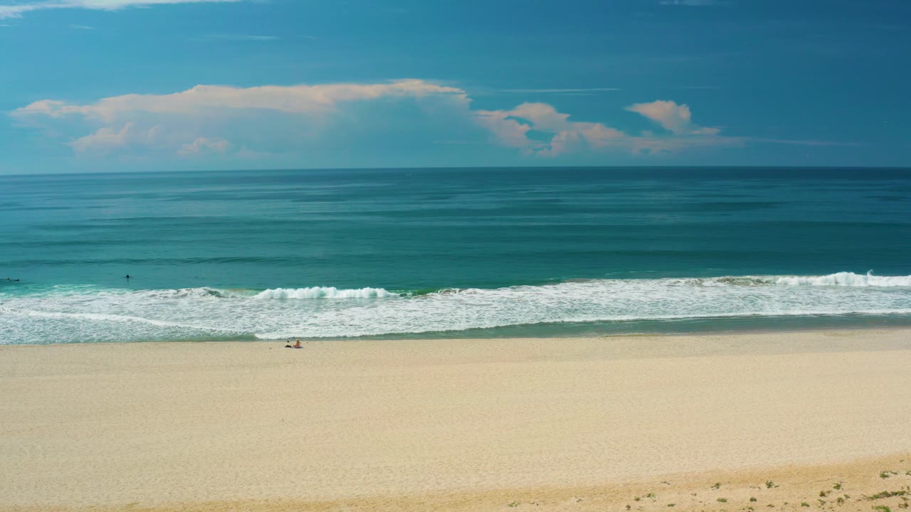 Open shoreline with white waves and distant cloud bank