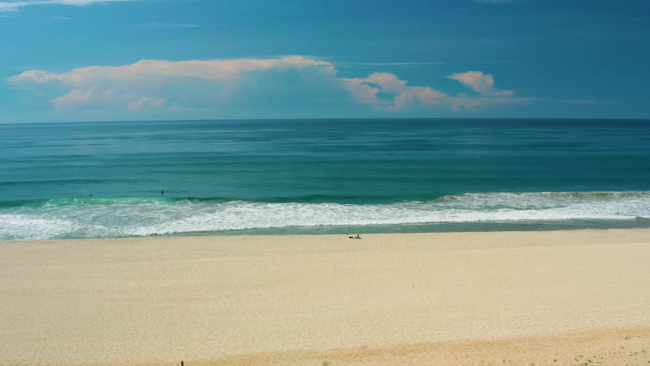 Wide San Jose del Cabo oceanfront frame with more whitewater spread across the surf line, empty-looking sand, teal water, and no discernible people.