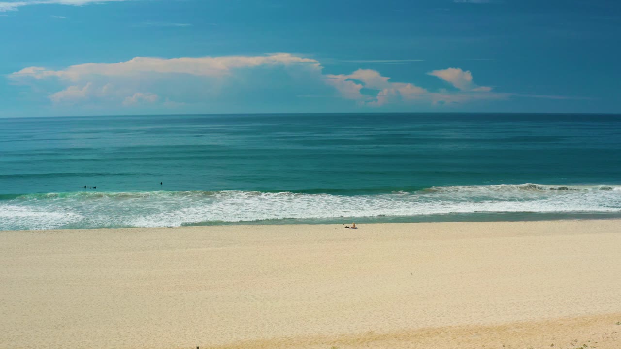 Horizontal bands of sand, surf, ocean, and sky