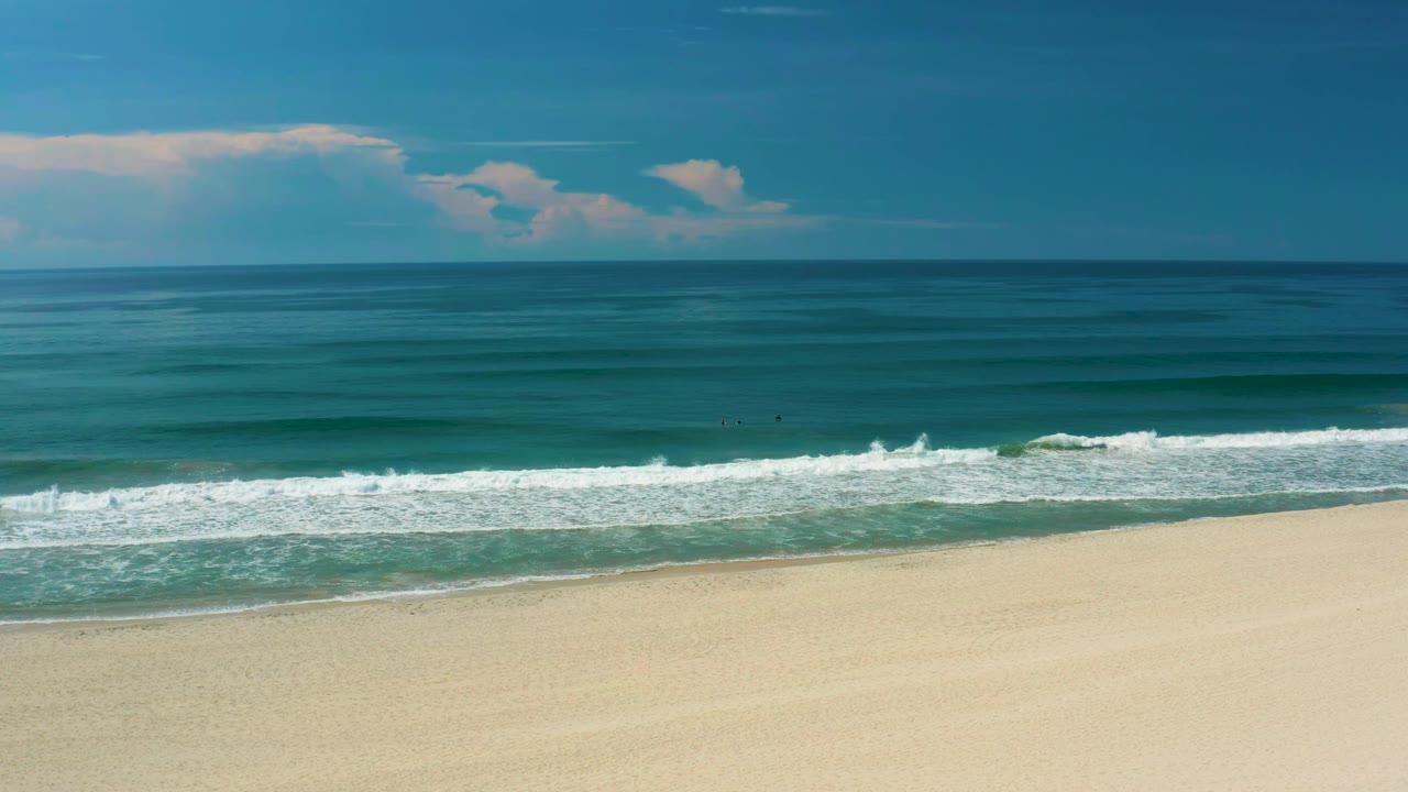 At 0:01, the San Jose del Cabo shoreline remains open, with a small white breaker offshore, smooth sand in the lower frame, blue-green water, and no visible people.