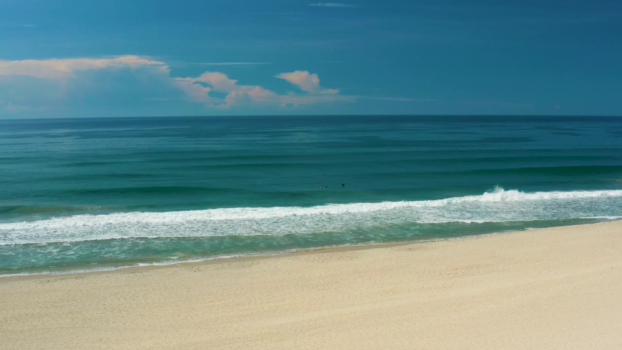 At 0:02, the frame holds a wide San Jose del Cabo ocean horizon, parallel bands of darker water, white surf near shore, empty sand, and no visible people.
