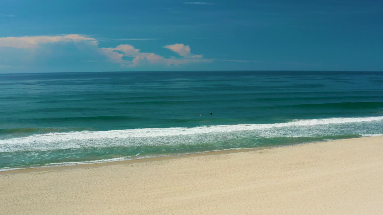 At 0:03, the San Jose del Cabo beach fills the lower frame while a long white surf band crosses the middle, teal ocean stretches beyond it, and no visible people appear.