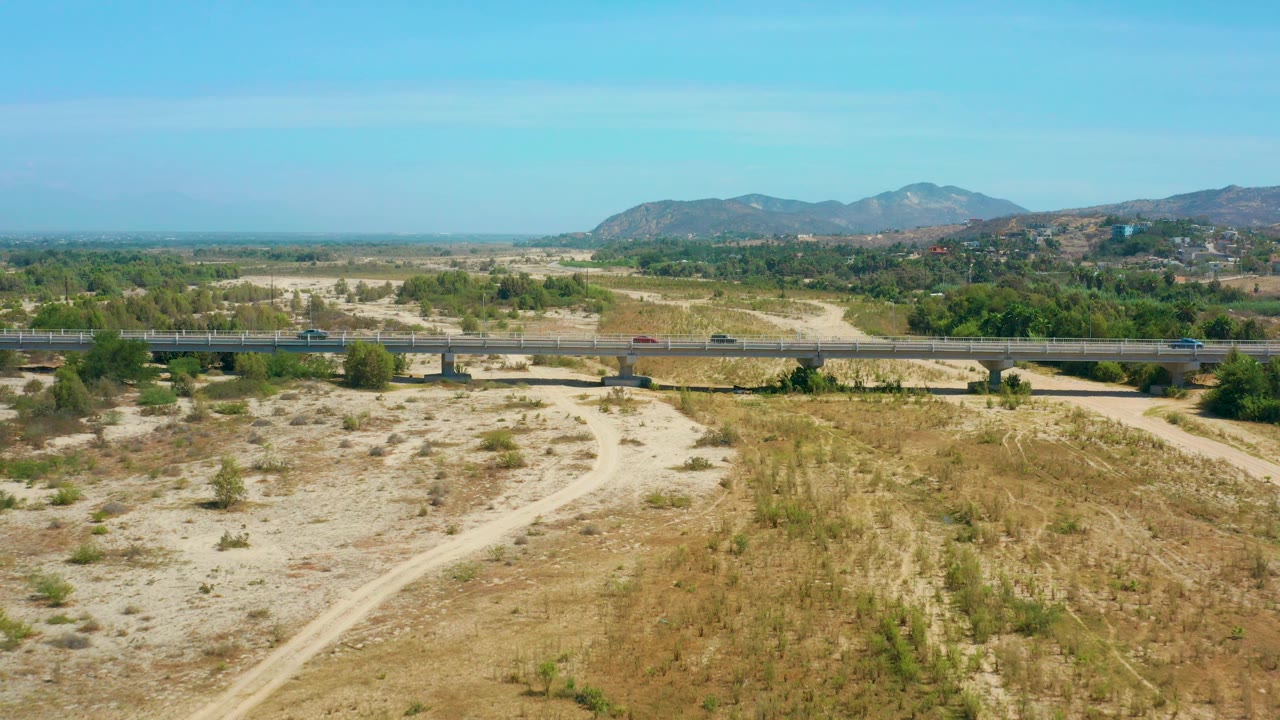 Bridge with several cars crossing a dry expanse under a clear sky