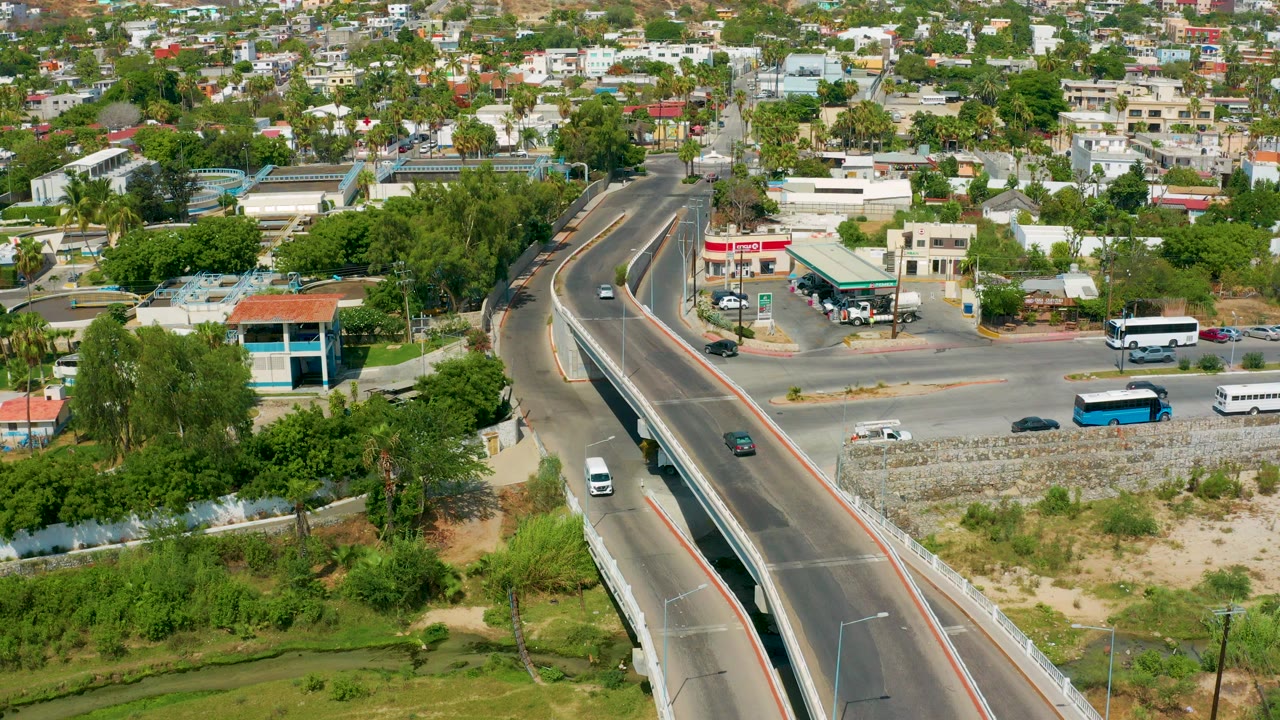 Aerial view of an overpass, vehicles, homes, and green vegetation.