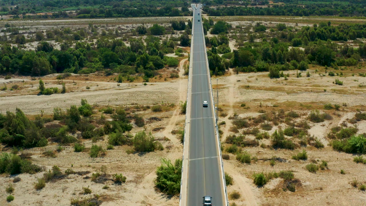 A later frame shows the San Jose Del Cabo road still centered, with the car lower in the frame, scrubby tan ground on both sides, and no visible people.