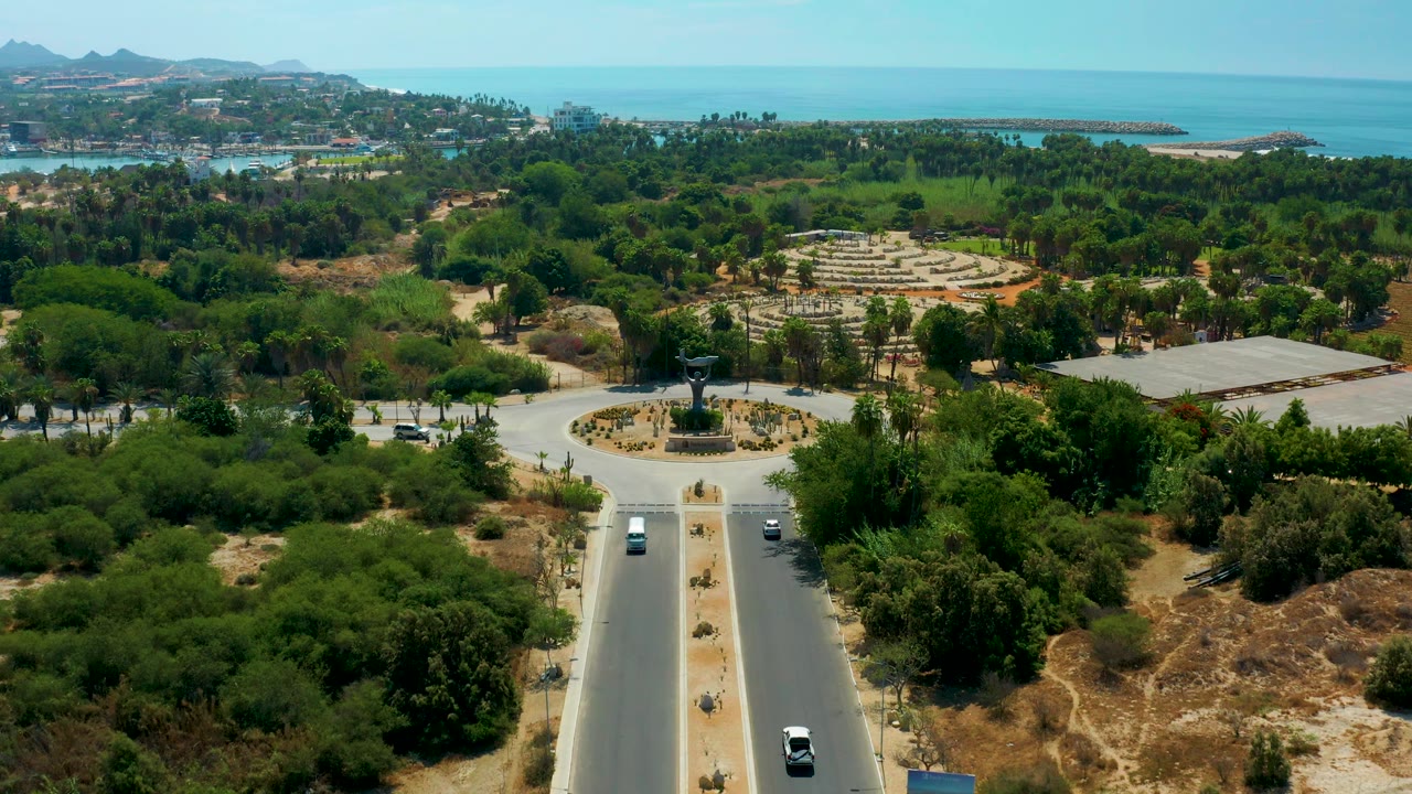 Aerial coastal city view with a sculpture roundabout and light road traffic