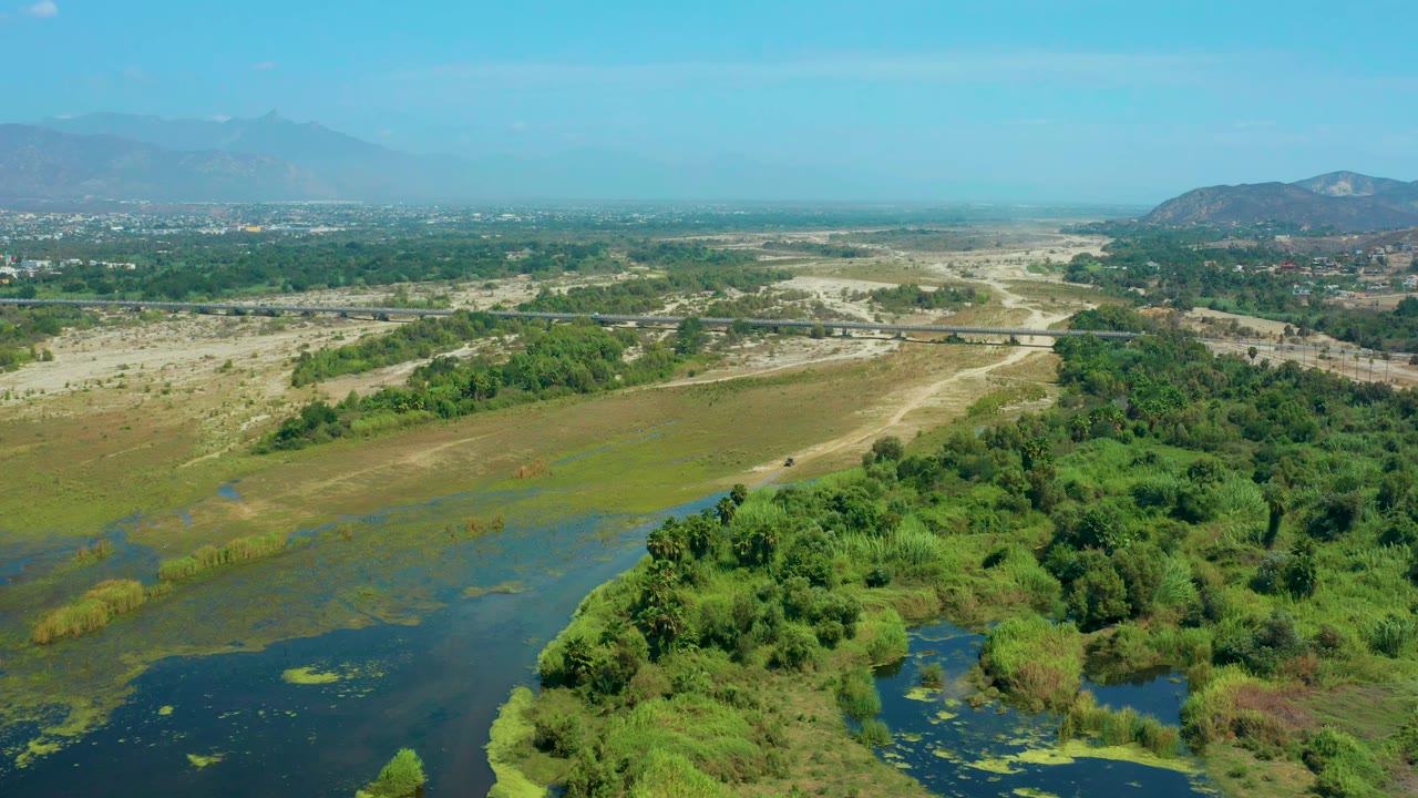 Aerial landscape with marshy water in the foreground and pale open land beyond.