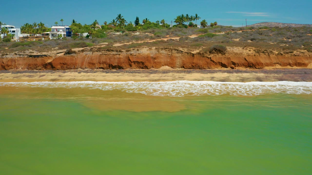 Coastal bluff with breaking waves and houses on the ridge