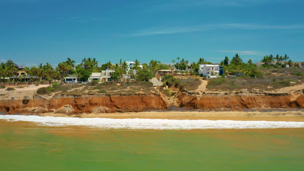 Closer coastal bluff section with surf and hillside houses