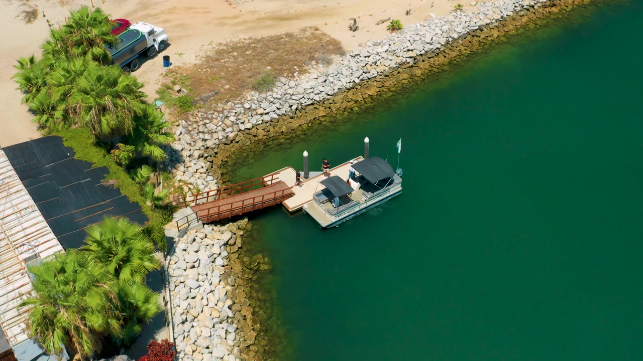 High-angle shoreline view with a boat at the end of a wooden dock.