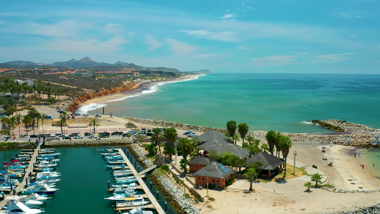 Aerial coastline with boats, huts, beach sand, and distant hills
