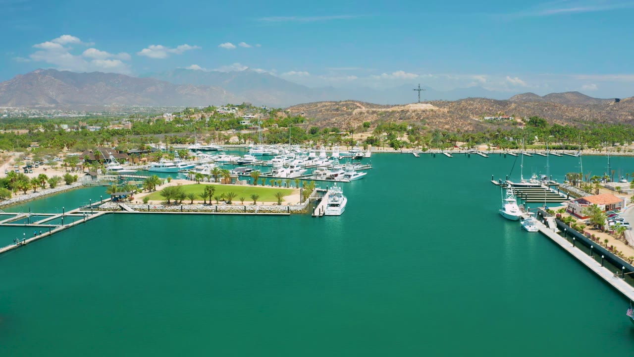 High view across green-blue marina water toward yachts and dry hills.