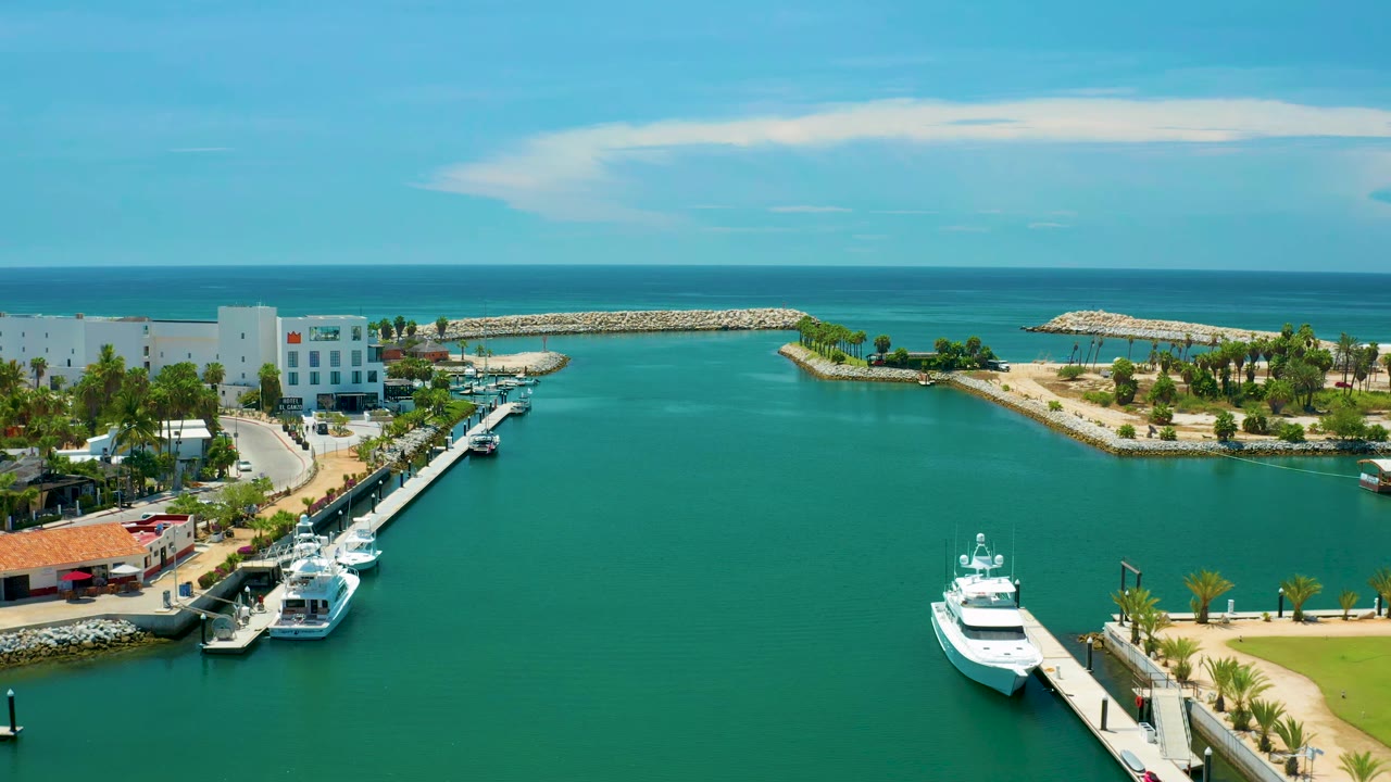 Aerial marina view with yachts at docks and a white coastal building near breakwaters