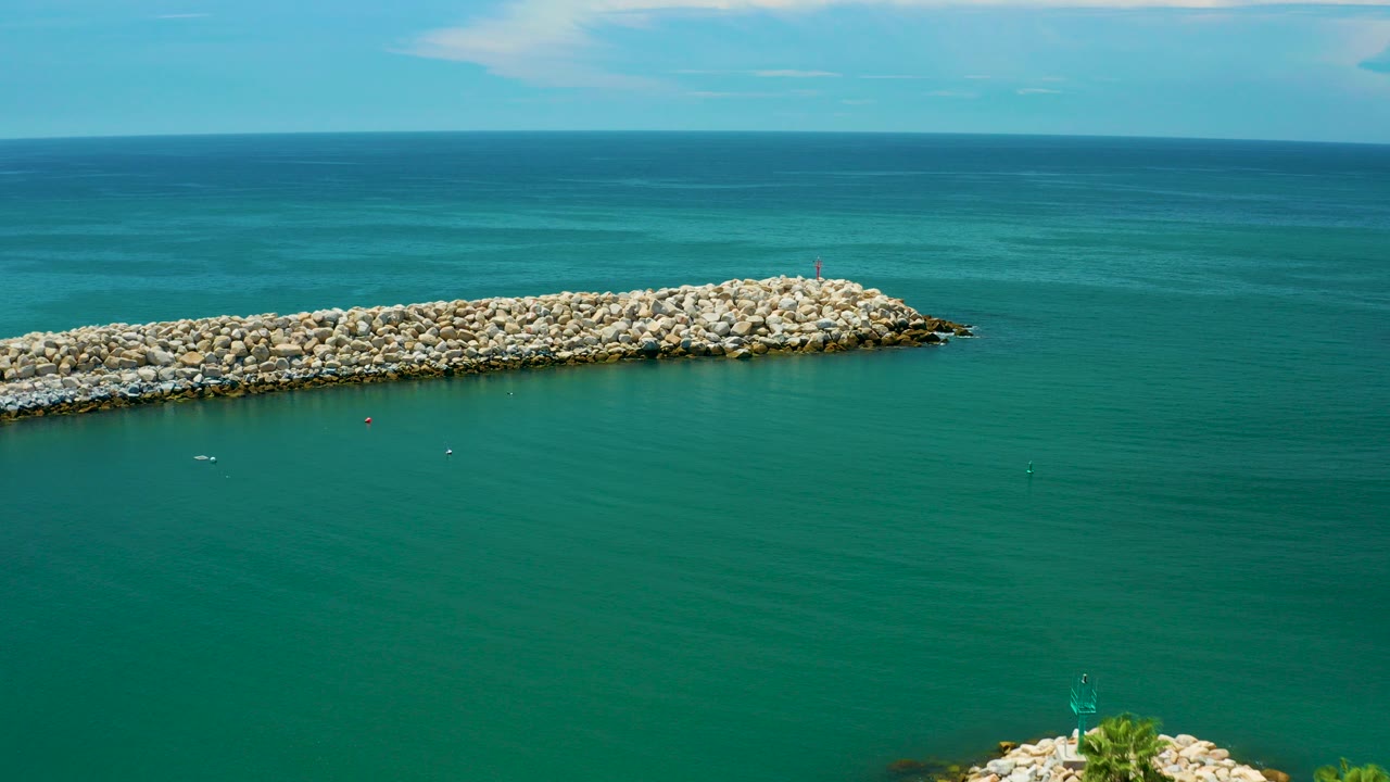 Elevated view of turquoise ocean water and a pale rock breakwater in San Jose Del Cabo, Mexico, with a clear horizon and no visible people.