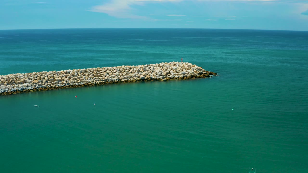 High coastal view in San Jose Del Cabo, Mexico showing the stone breakwater beneath a blue ocean horizon, with open water in front and no visible people.