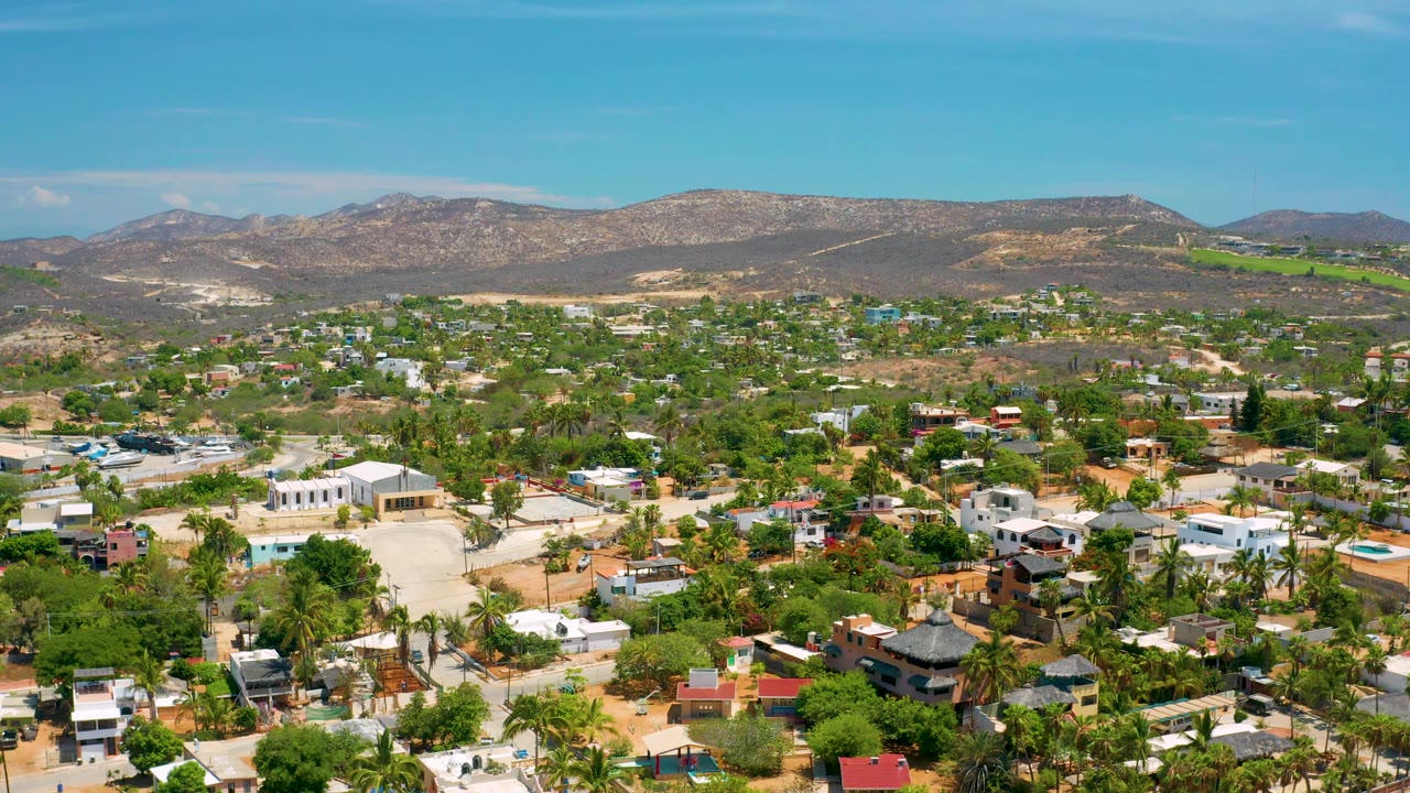 Aerial city panorama with white buildings and mountains under clear sky.