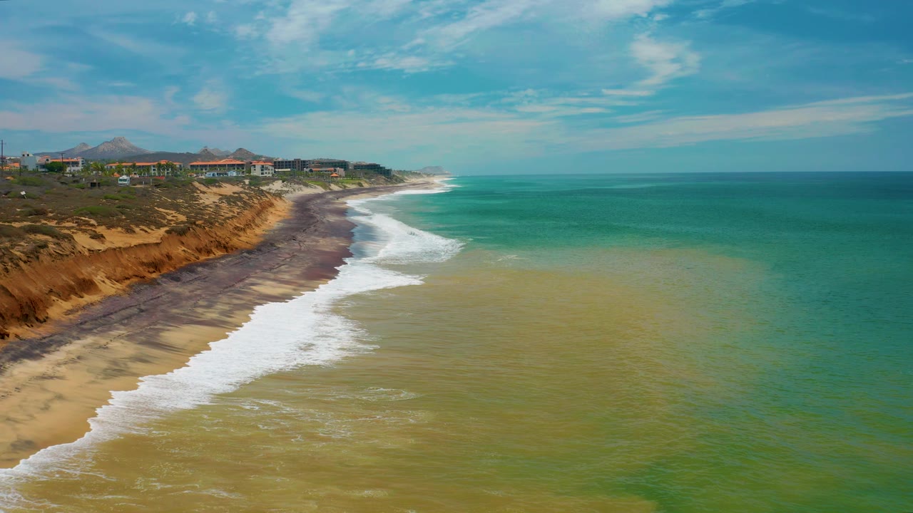 Drone view of surf line, orange bluff, beach, and open ocean.