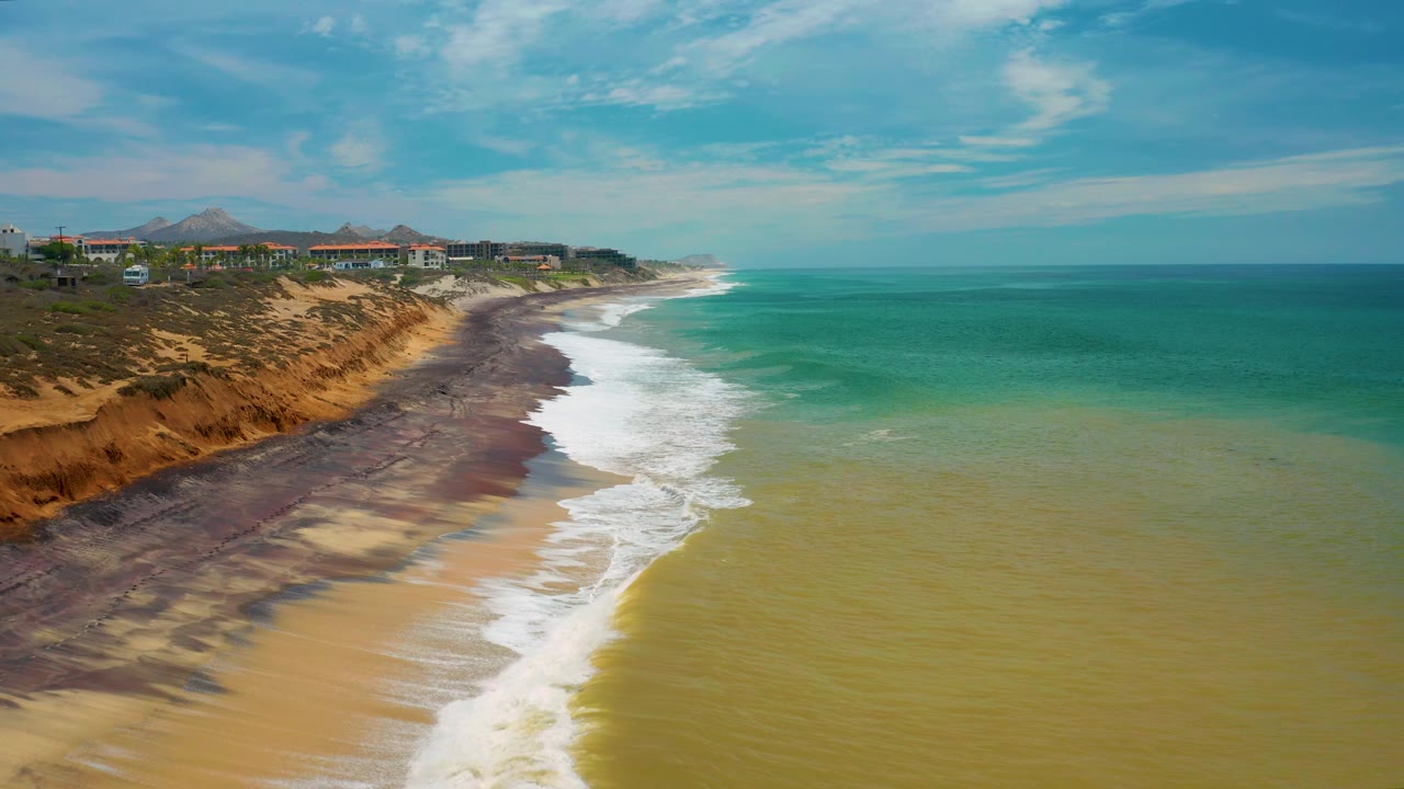 Aerial view of waves breaking along a bluff-backed beach.