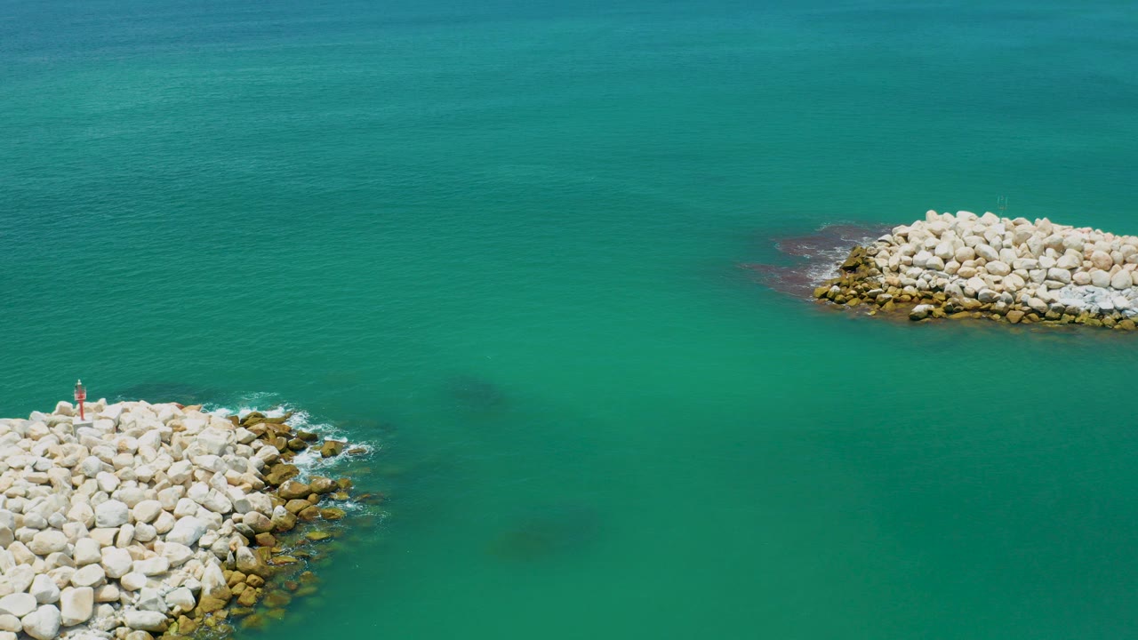 Turquoise sea with pale rock breakwaters at opposite edges.
