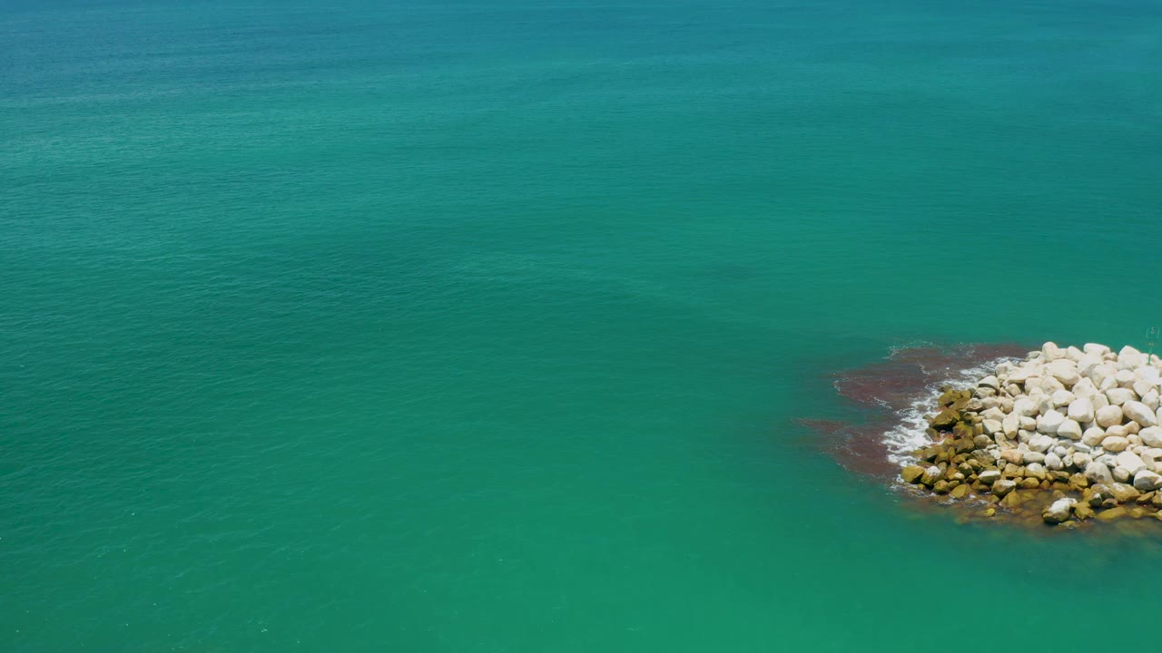 Rock cluster in green water with small wave foam