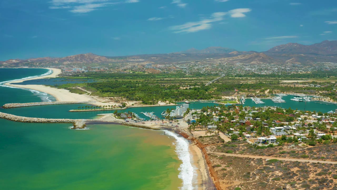 Drone view of sandy shoreline and marina beside town