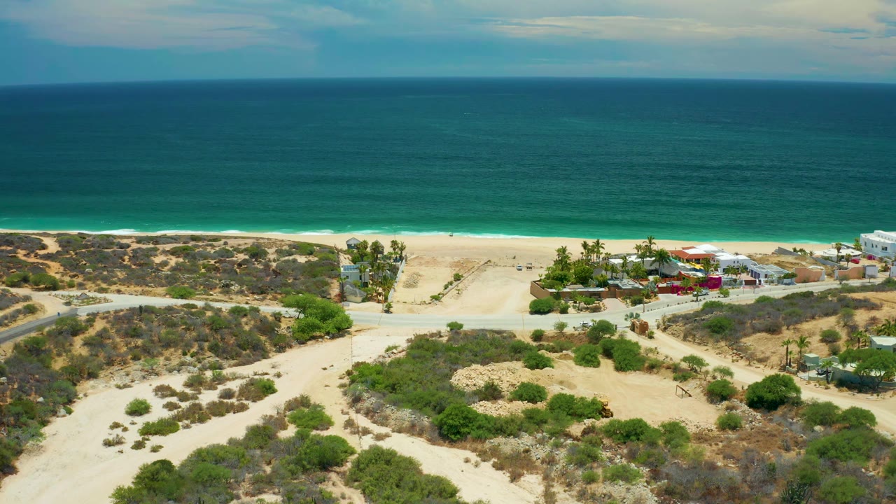 Wide drone view of sand trails leading toward beach and ocean