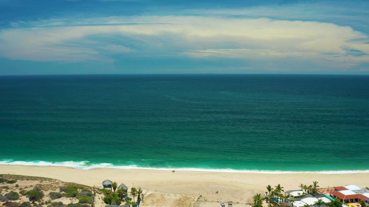 Clouded sky over a wide ocean and empty beach edge.
