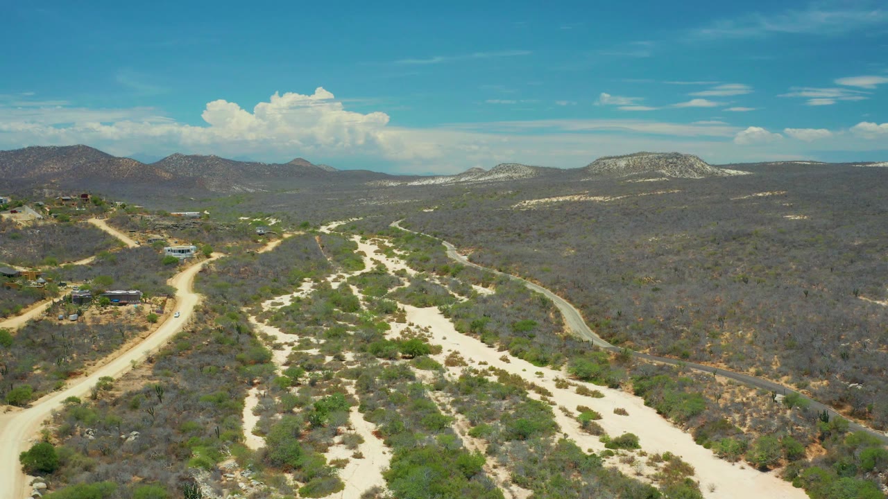 Aerial desert wash with dirt road and scrub-covered hills