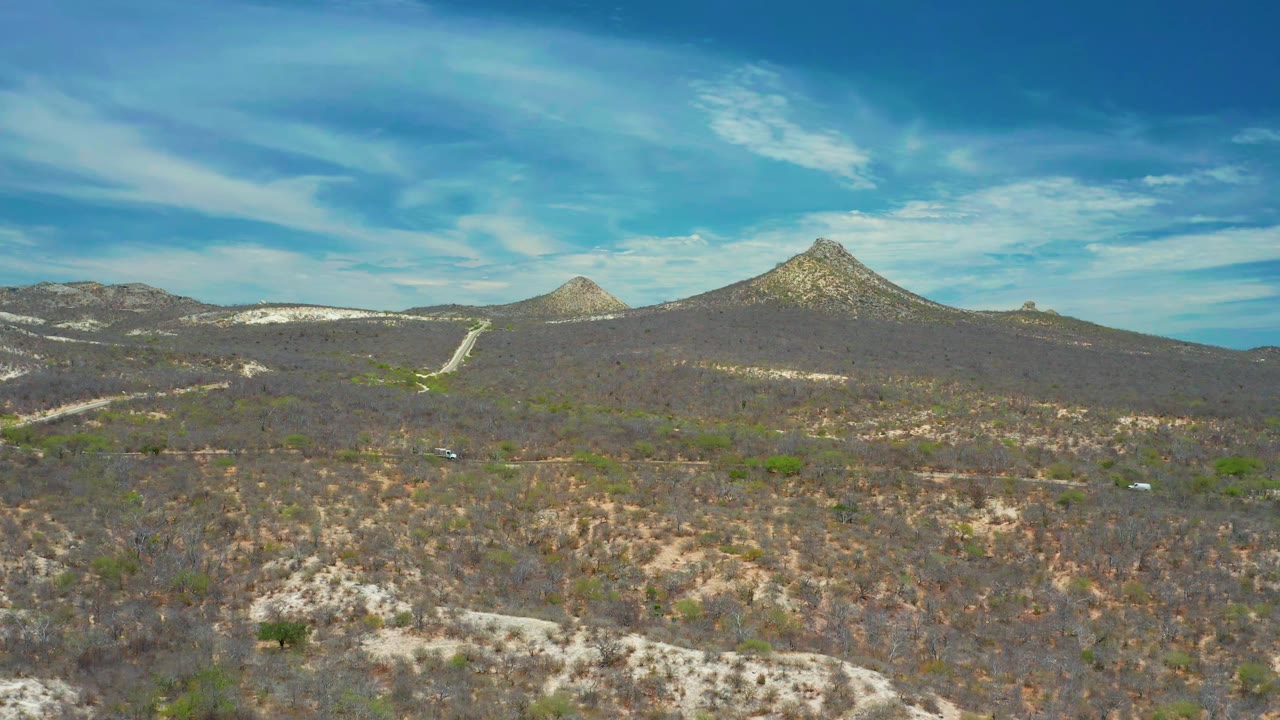 Dry mountain terrain with dirt tracks crossing the hillsides.