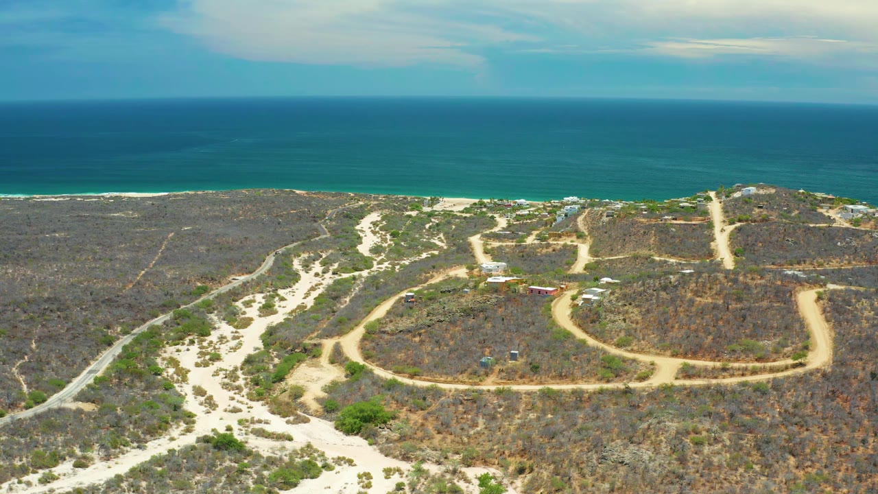 Dirt tracks curve through scrubland toward the ocean