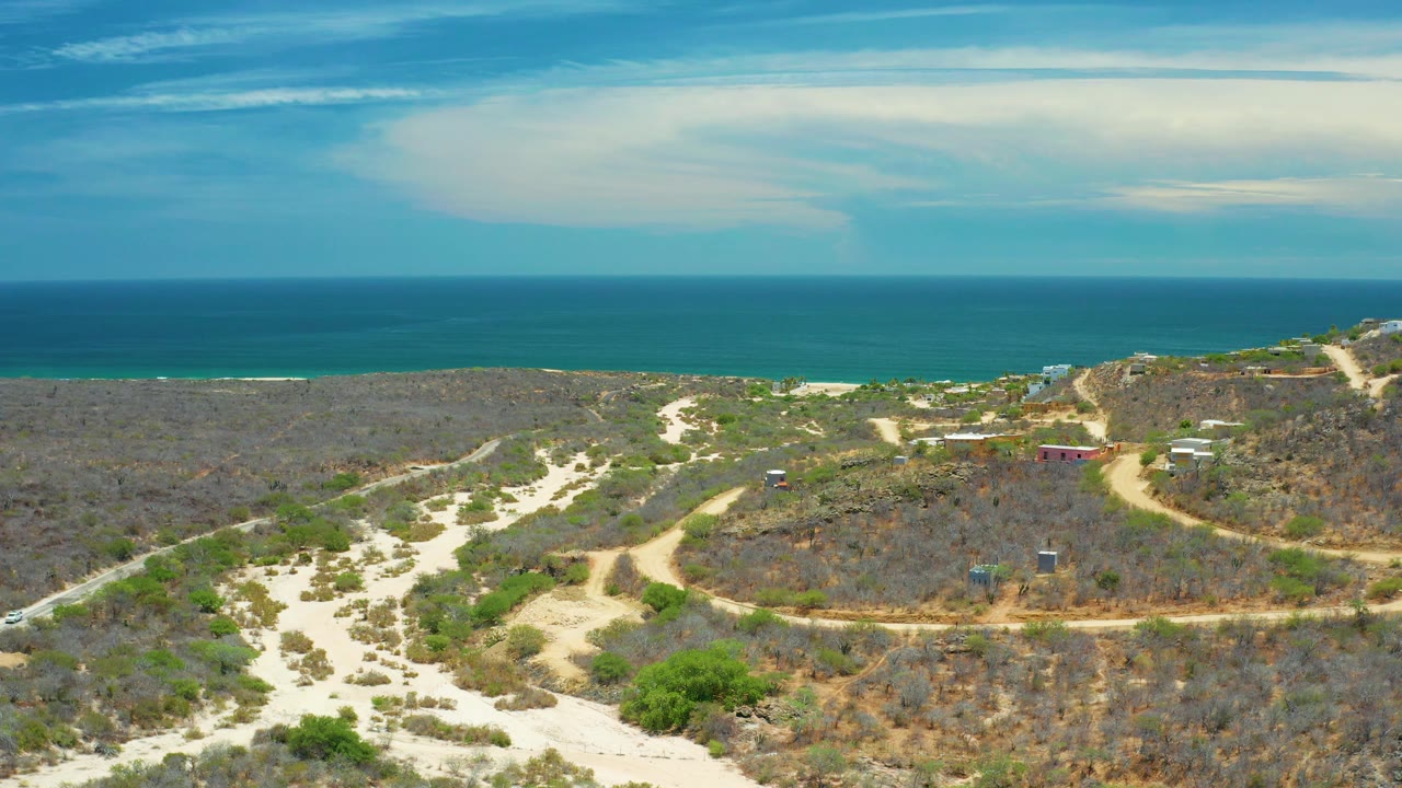 Pale dirt roads crossing brushy coastal land toward the sea.