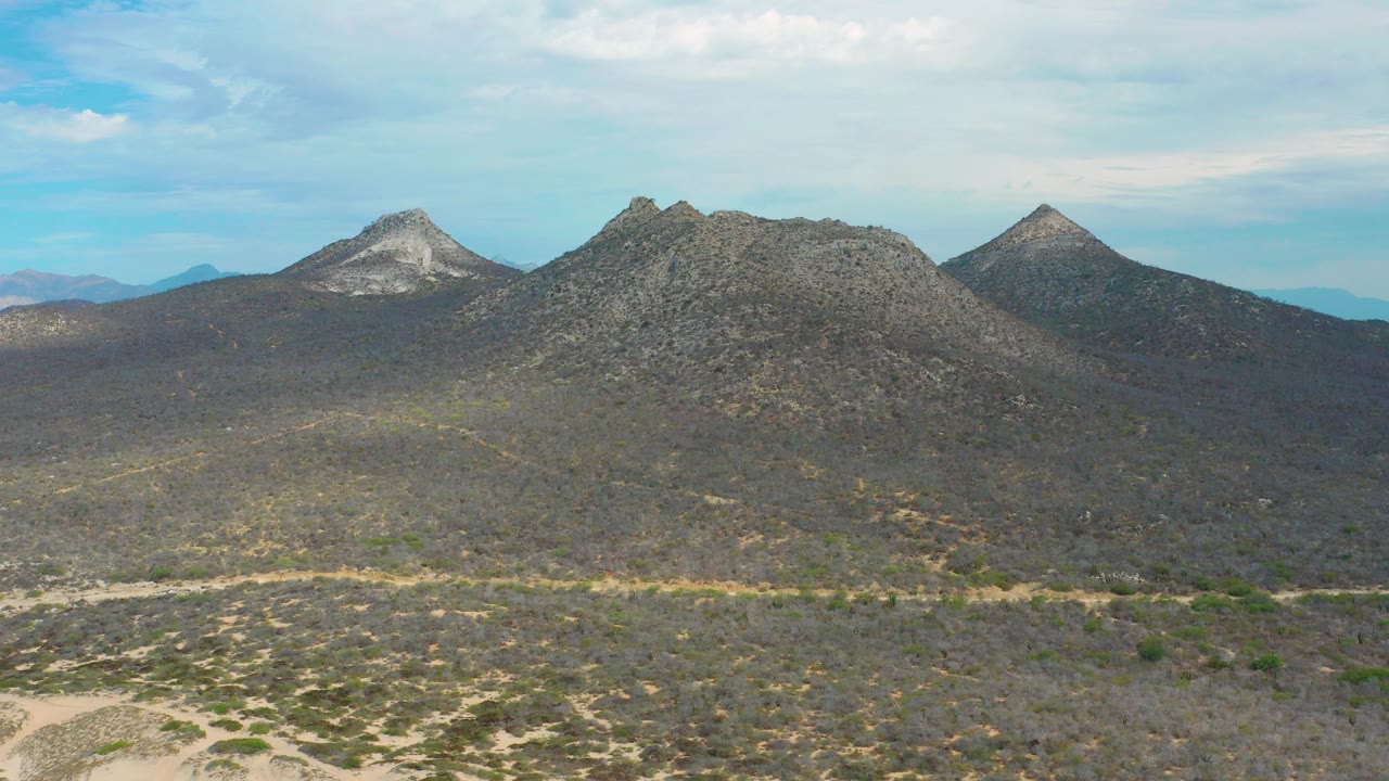 Wide view of dark rocky slopes and mountain peaks in Laguna Beach, Baja California Sur, with low desert vegetation and no visible people.