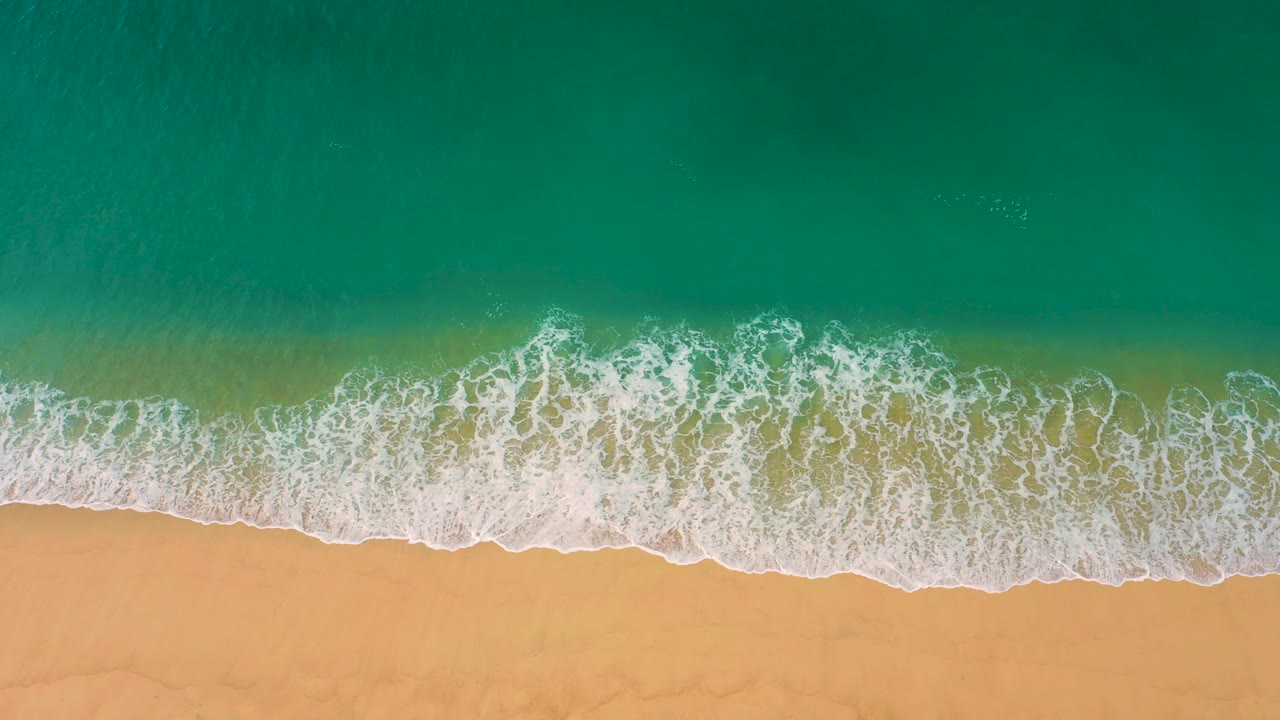 A foamy wave band sits lower in the frame as clear green-blue water fills the top at Laguna Beach, Baja California Sur, with no visible people.